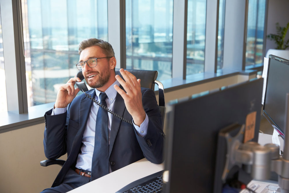 Businessman Making Phone Call Sitting At Desk In Office | Tips On How To Sell SaaS | monthly recurring revenue