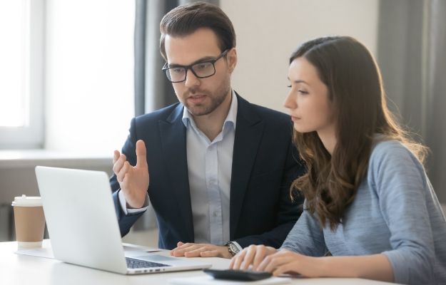 Helpful male boss mentor coach teacher explaining new online project to young female worker intern student | Open Communication